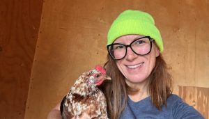 Lady holding a chicken in a chicken coop
